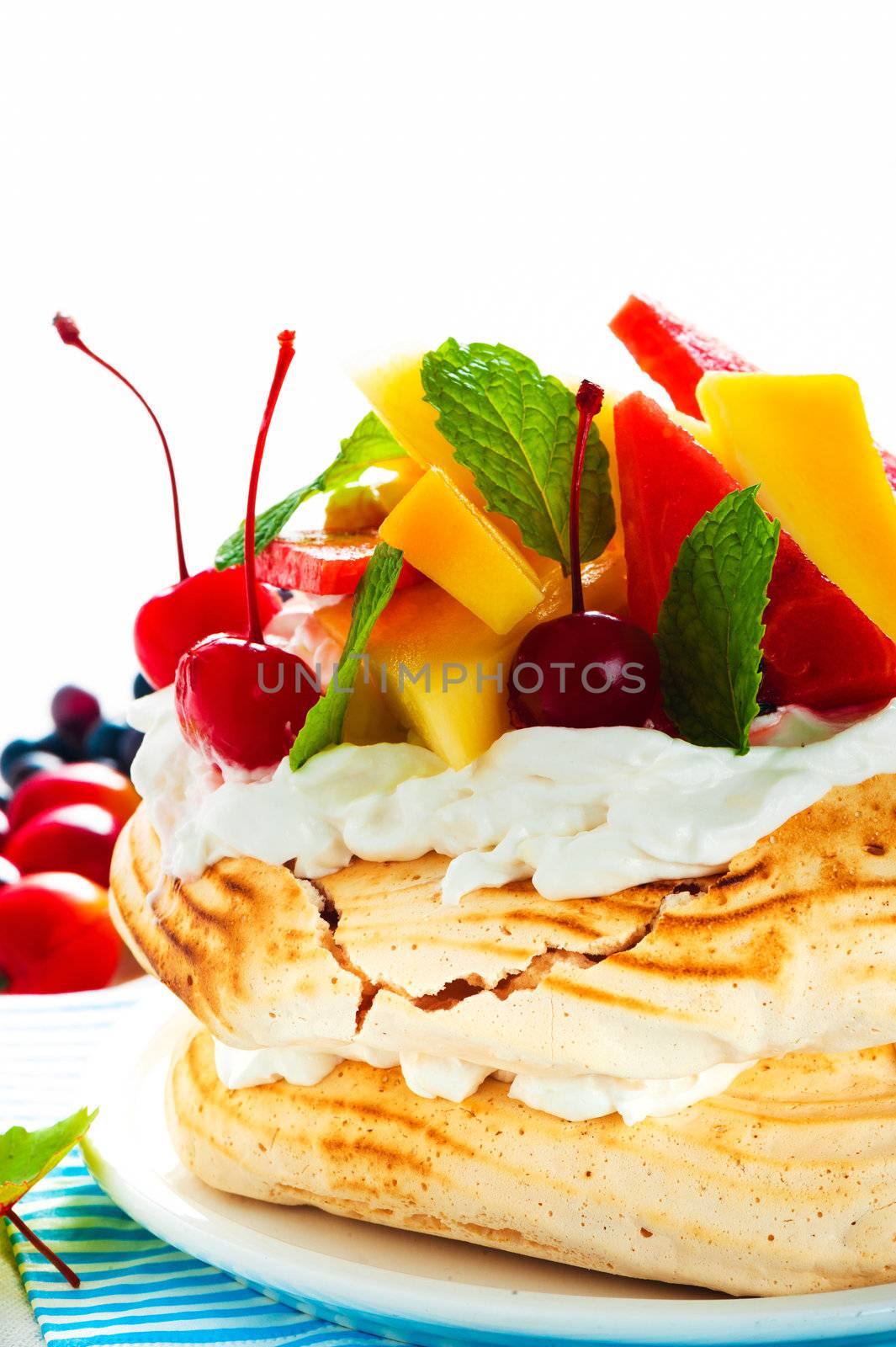 Pavlova with fresh fruit (mango, pineapple, watermelon, cherry) ready  to serve, on white background as a studio shot