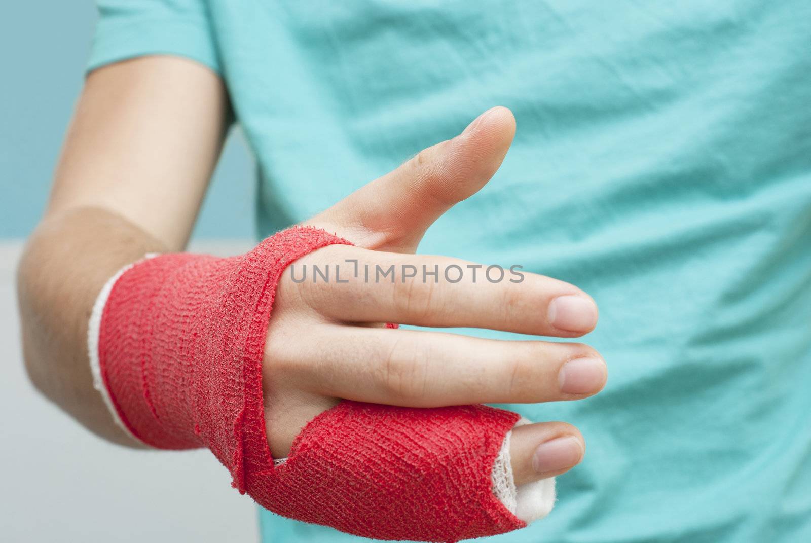 Injured male hand with upper part of body. Hand is bandaged with red plaster focus set on thumb