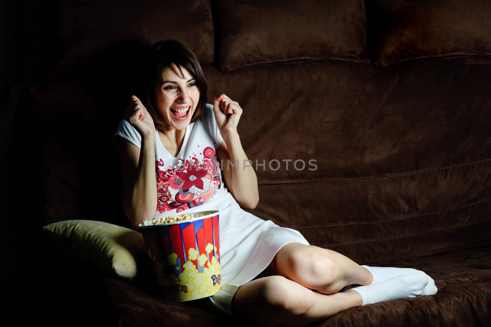 An image of a girl on a sofa watching TV