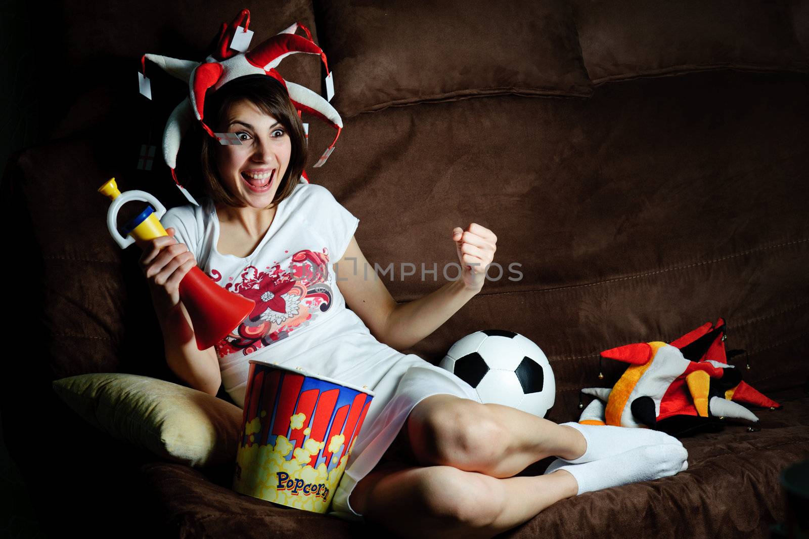 An image of a girl on a sofa watching football on TV