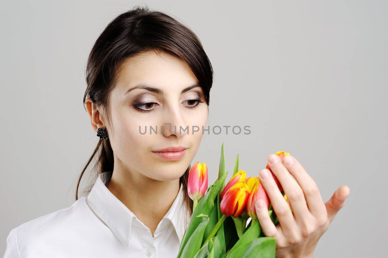 An image of young woman holding a bunch of orange tulips