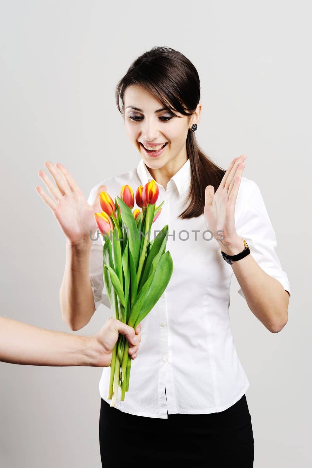 An image of young woman holding a bunch of orange tulips