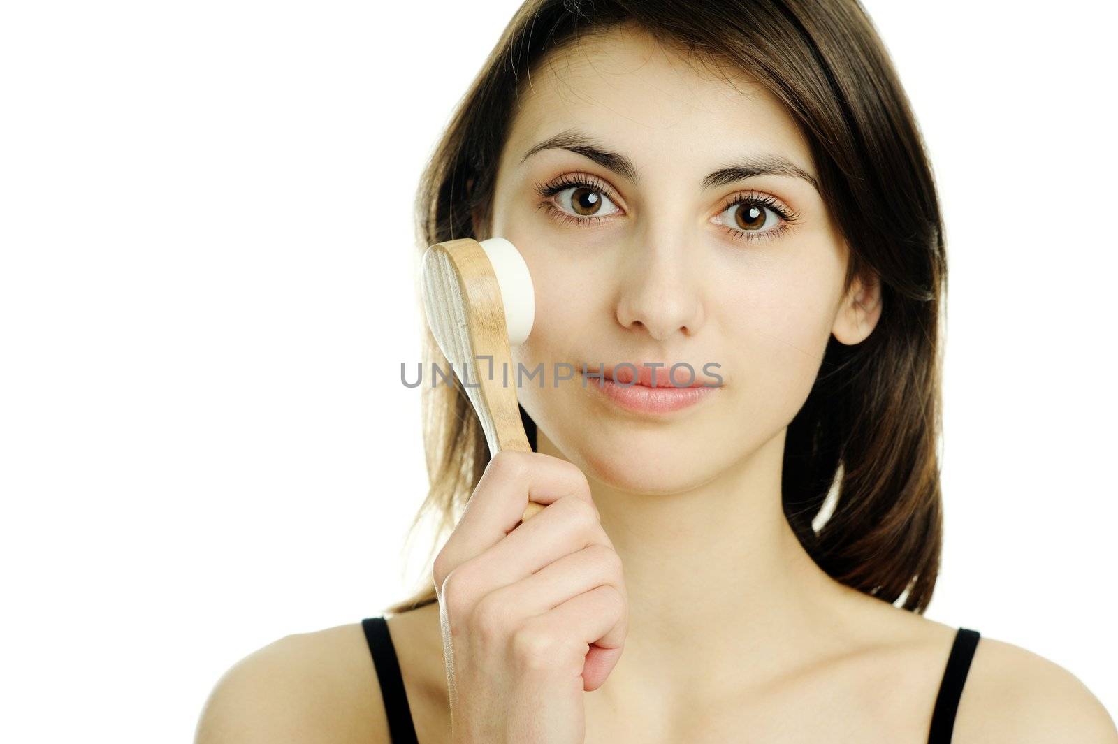 An image of a young woman cleaning her face