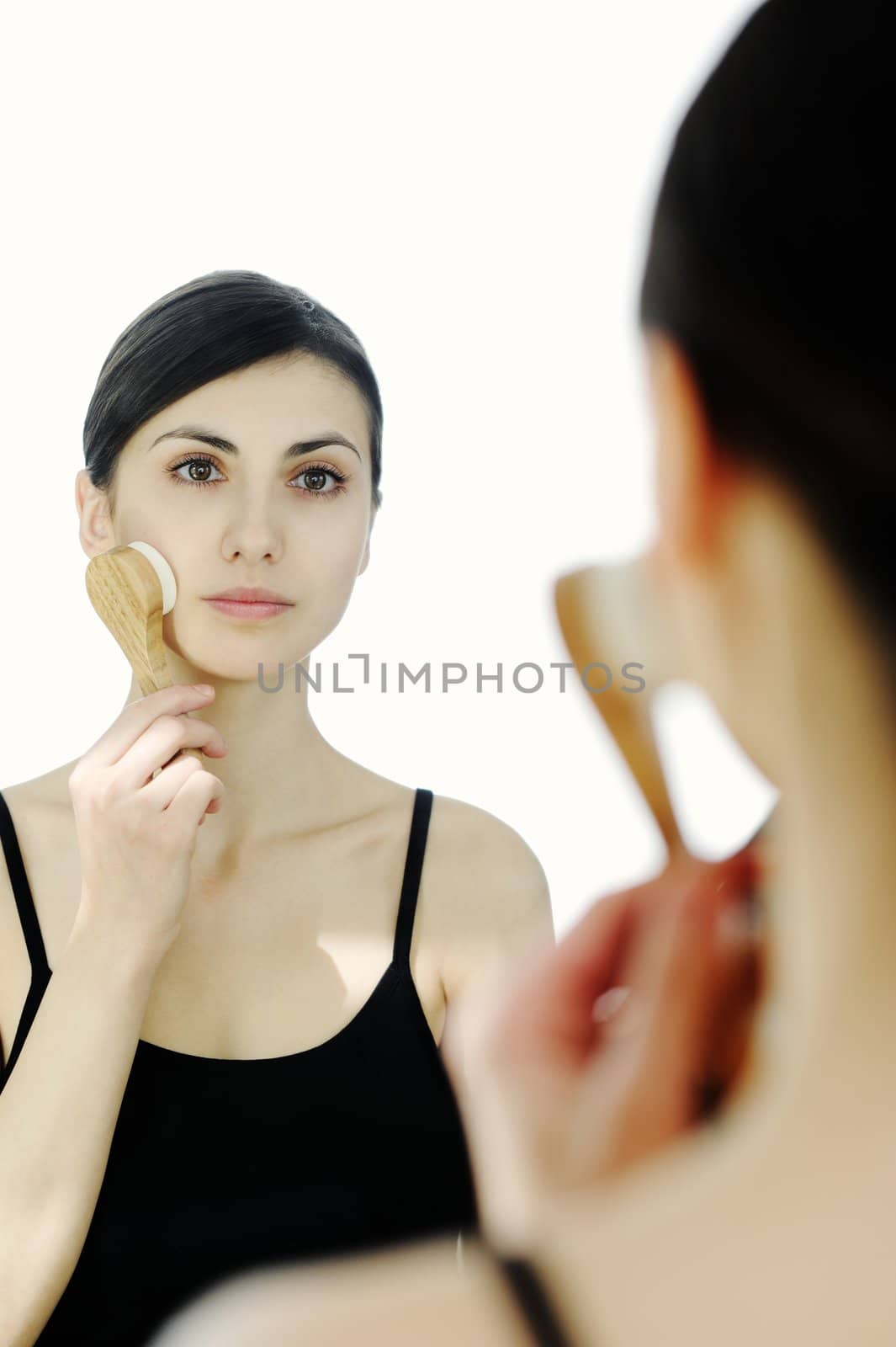 An image of a young woman cleaning her face with a brush