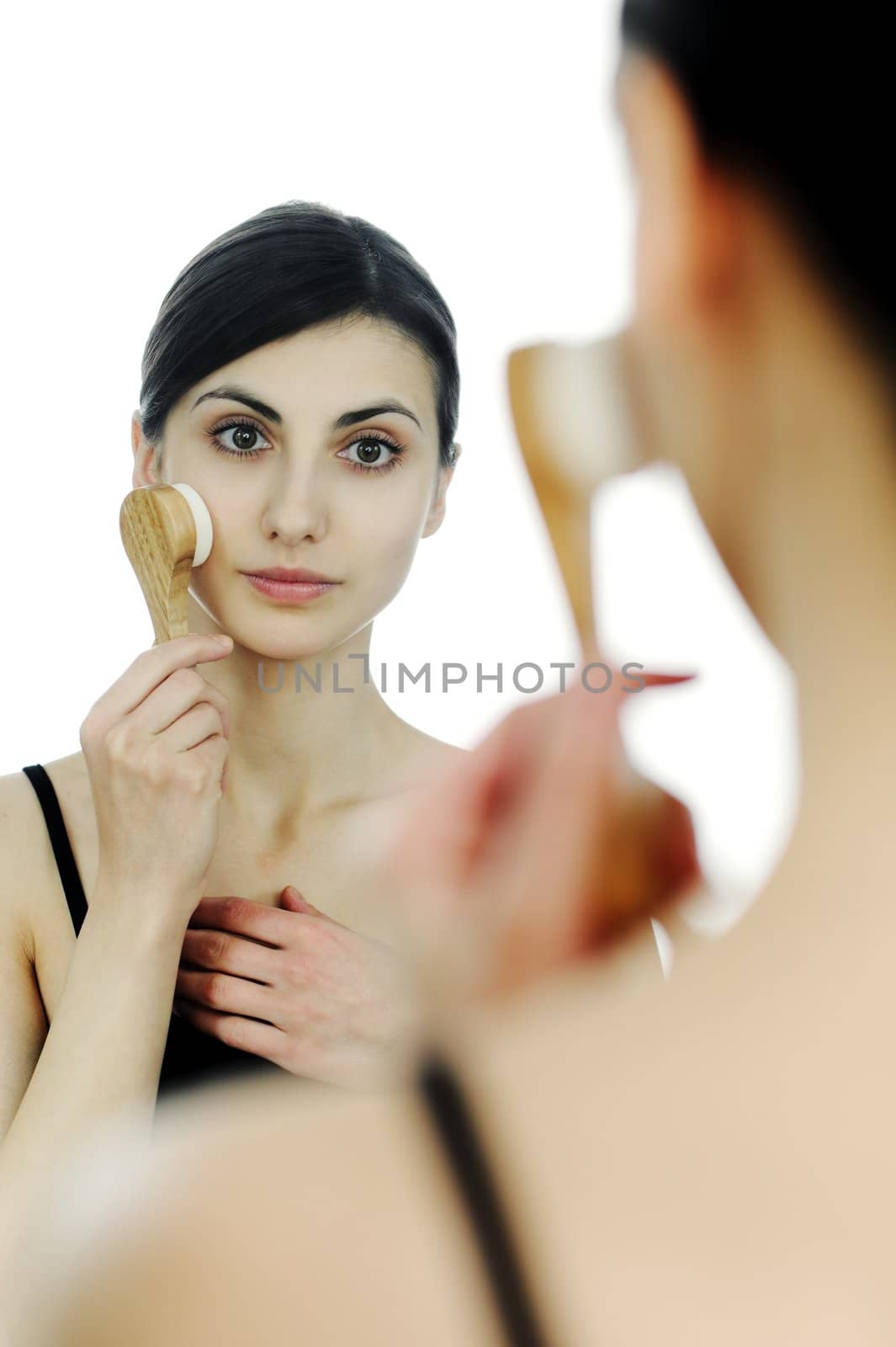 An image of a young woman cleaning her face with a brush