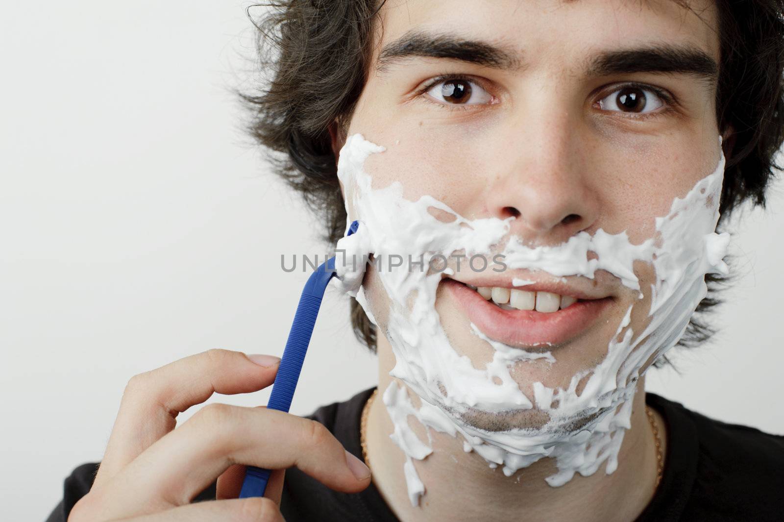 An image of a young handsome man shaving