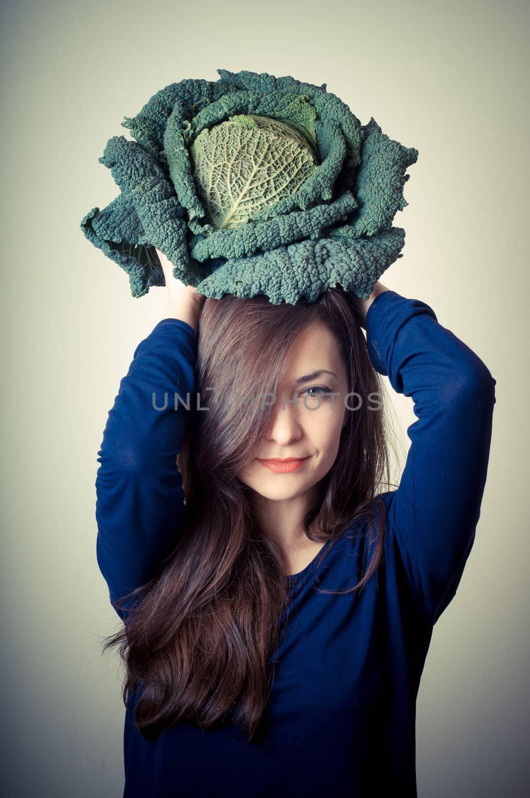 beautiful woman with savoy cabbage on gray background