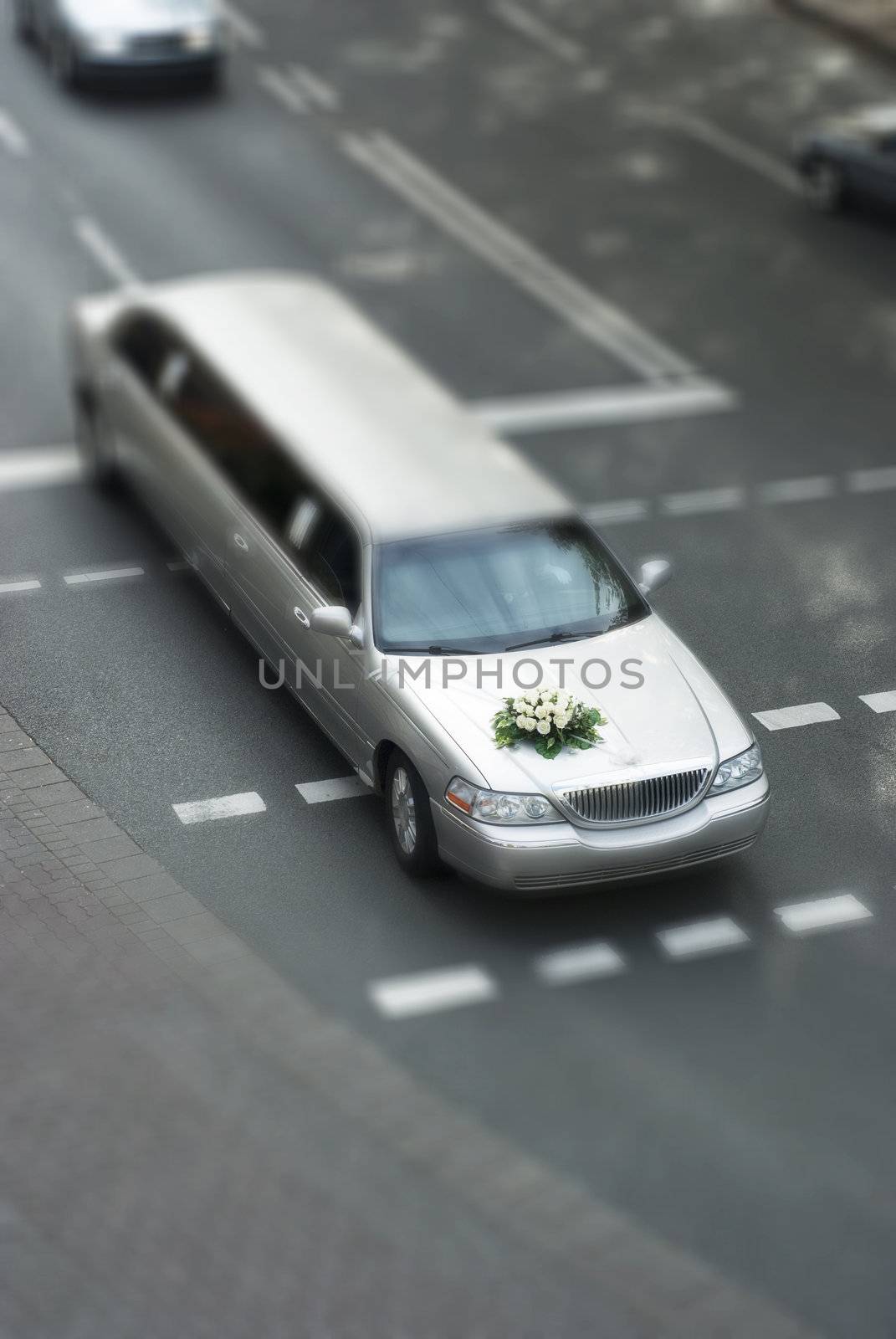 wedding limousine with blured traffic and tilt shift. The streched car has a bouquet on its hood