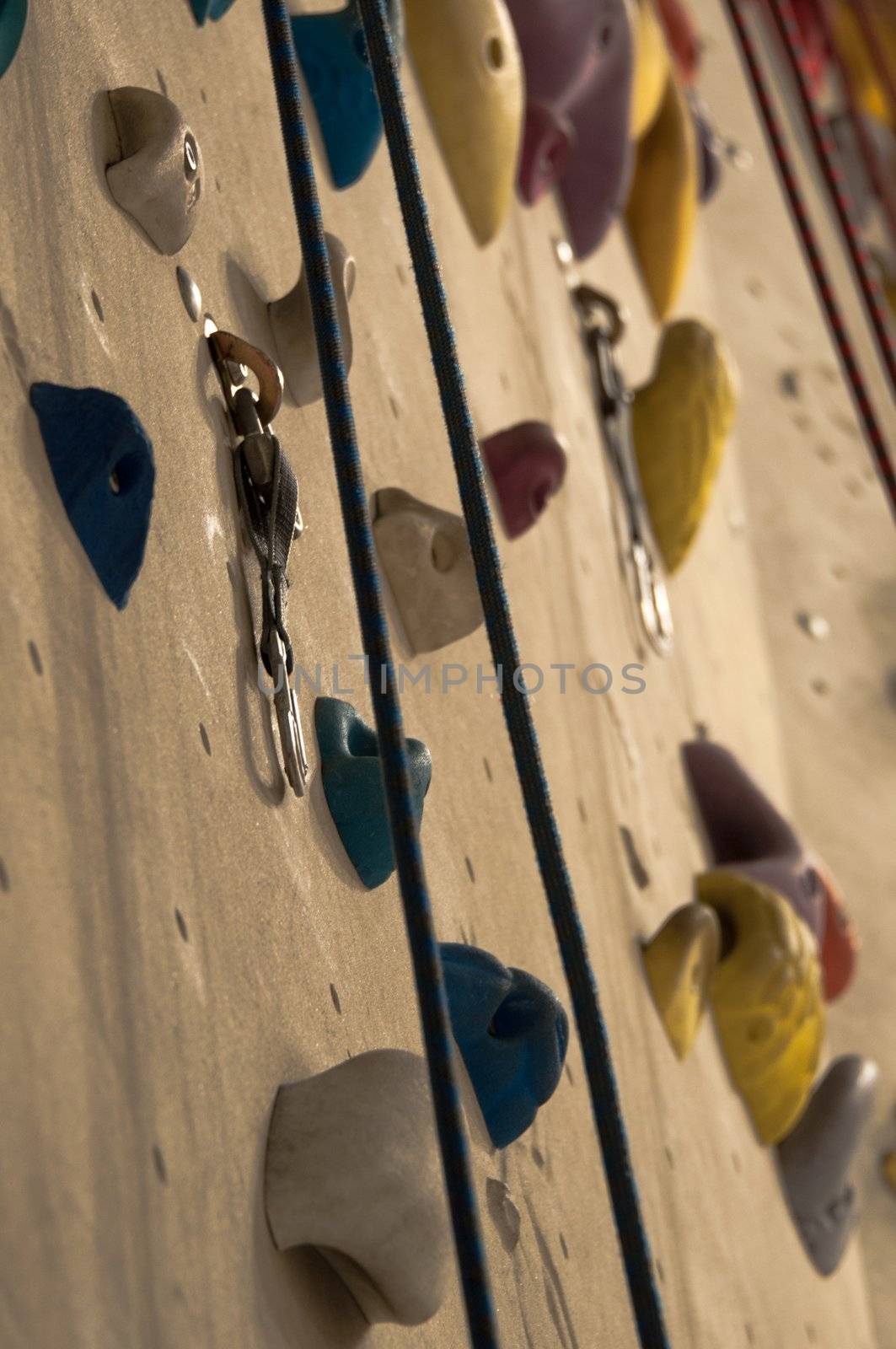 homemade artificial climbing wall covered with colored holds and ropes for rock climbing training