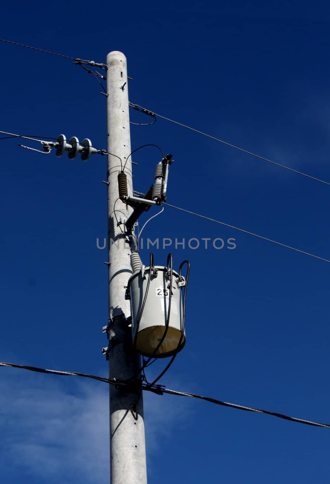 A single electric power transformer against a clear blue sky.