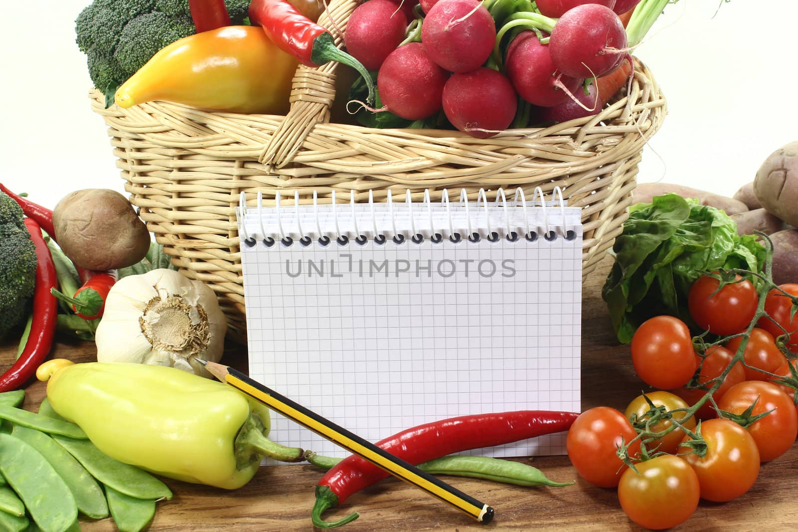 plaid shopping list with pencil, vegetables and basket on a wooden ground