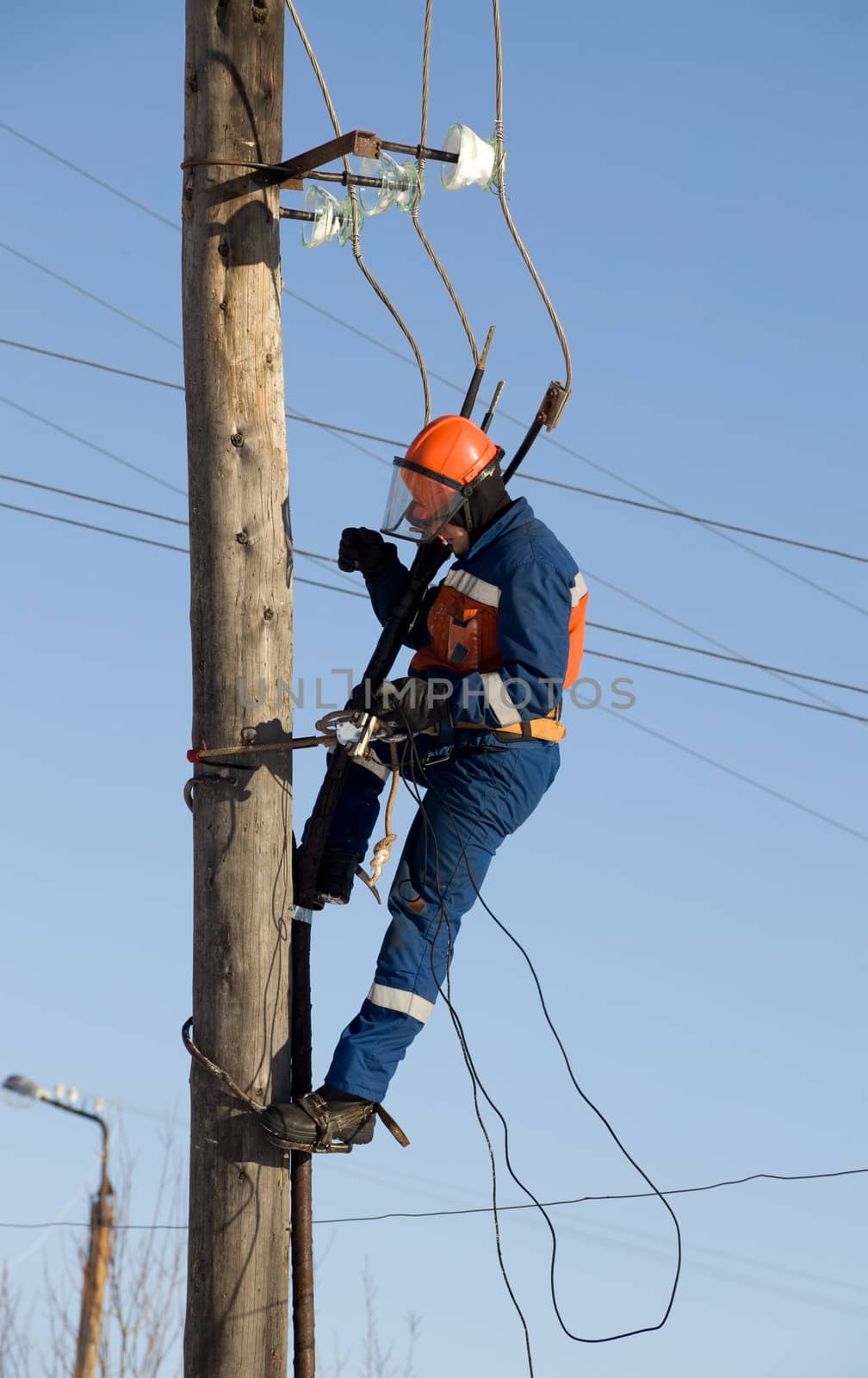 Electrician in blue overalls working at height with wires