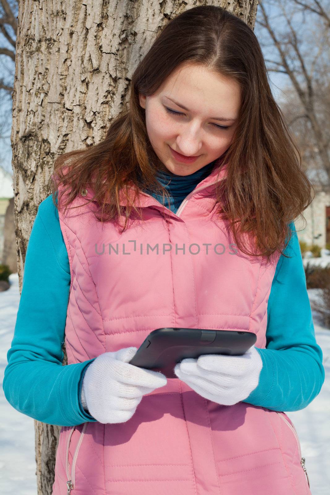 Teen girl with e-book reader in a park by AndreyKr
