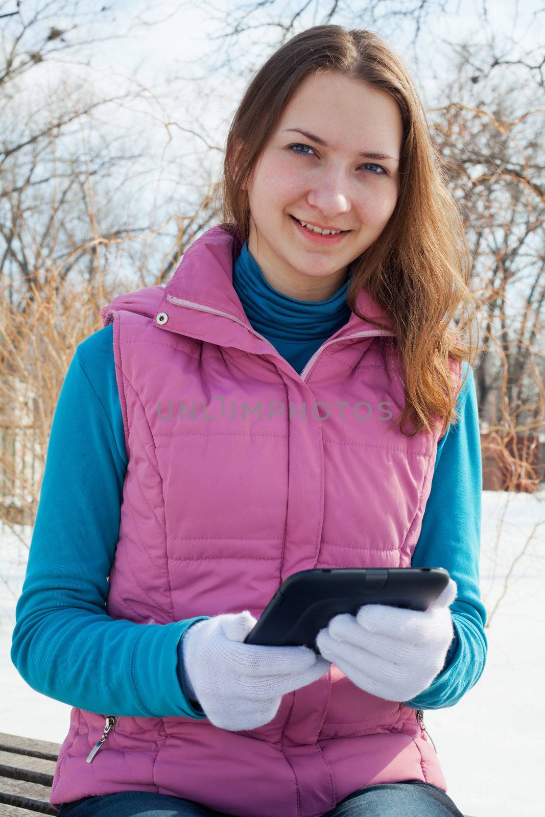 Teen girl with e-book reader in a park at winter time