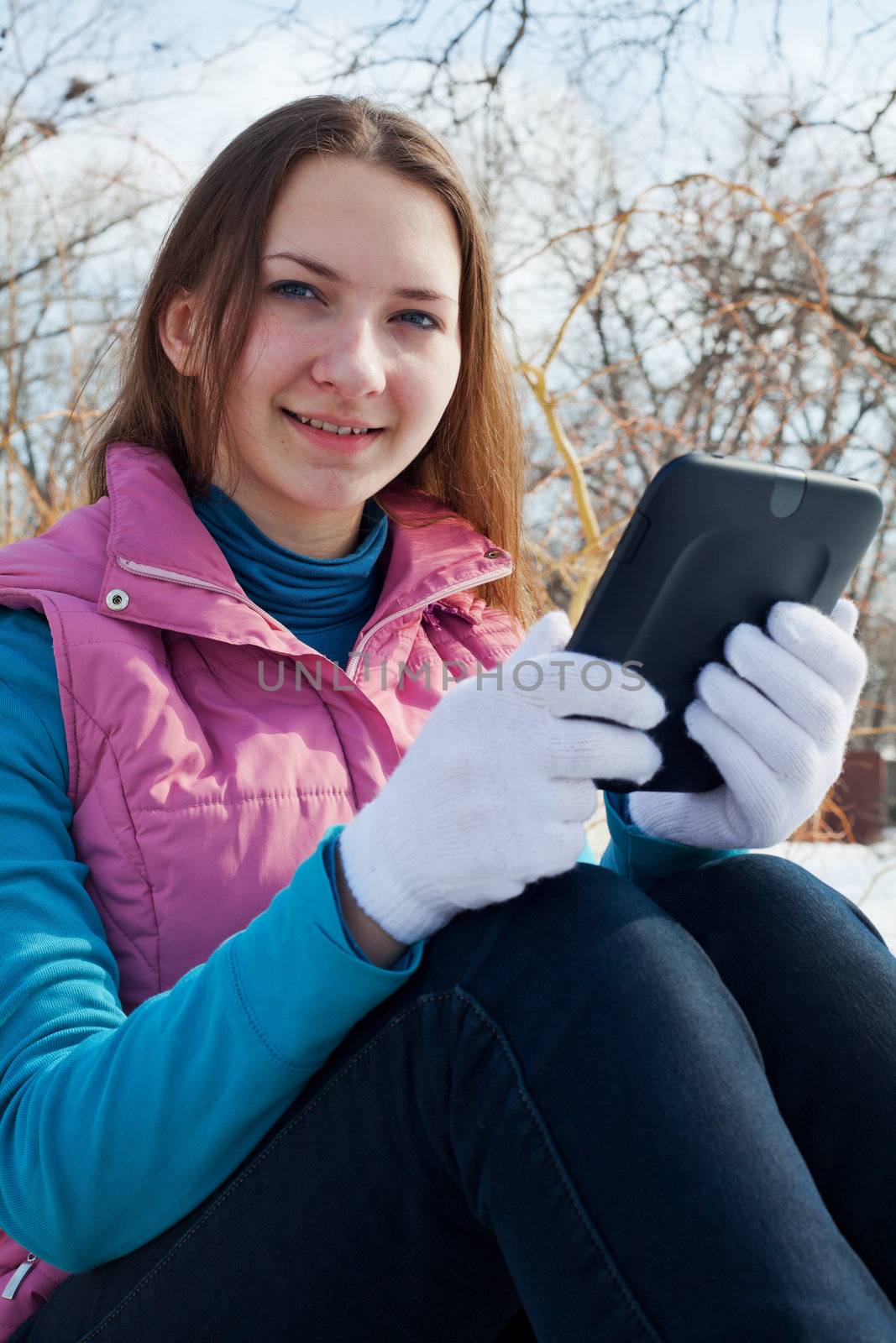 Teen girl with e-book reader in a park by AndreyKr