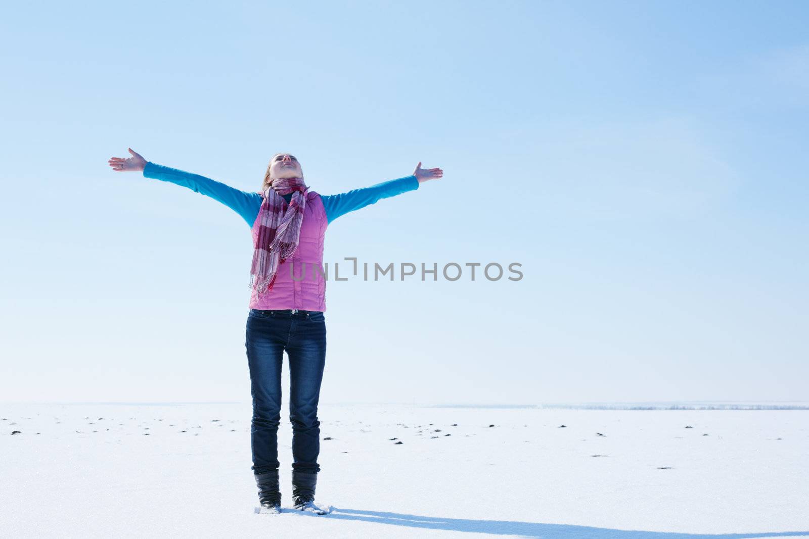 Teen girl staying with raised hands against blue sky