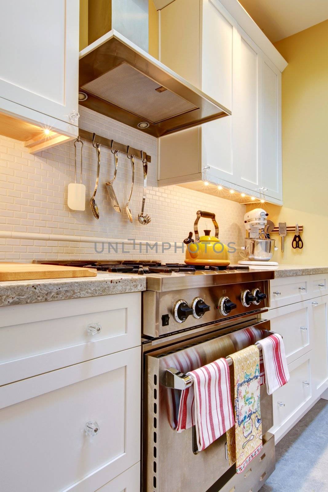 Close up of the white kitchen with stainless steal stove and hood.