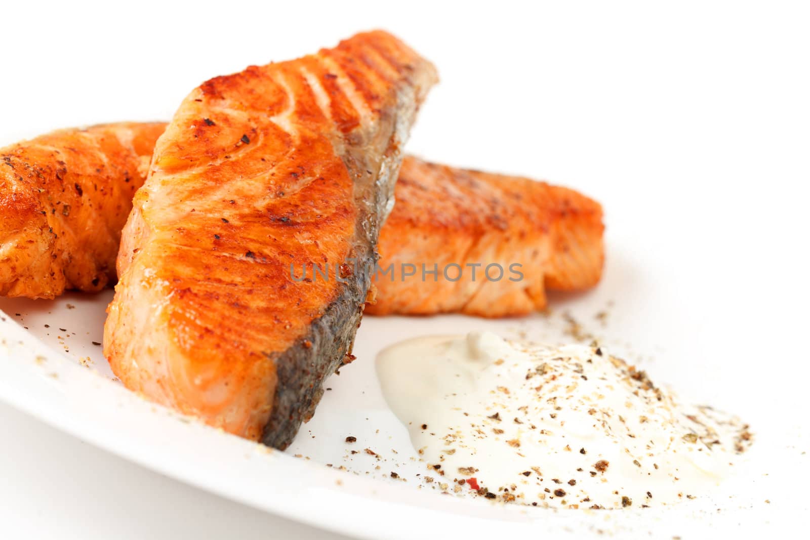 Fried salmon fillets with sauce on white plate