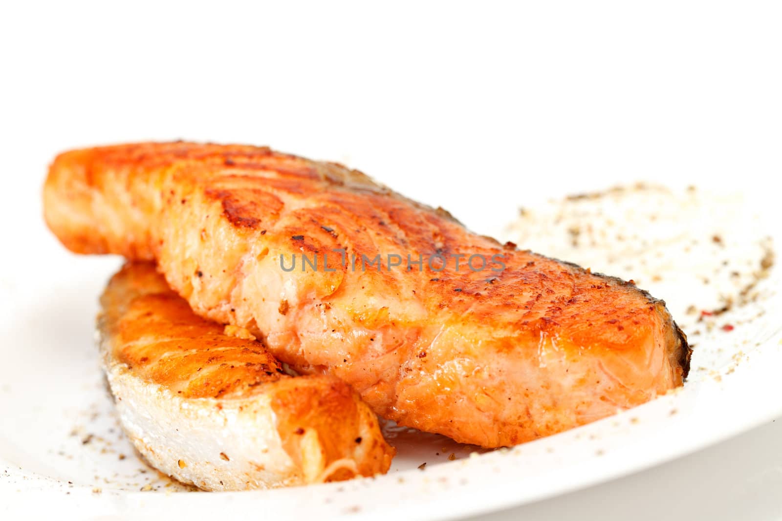 Fried salmon fillets with sauce on white plate