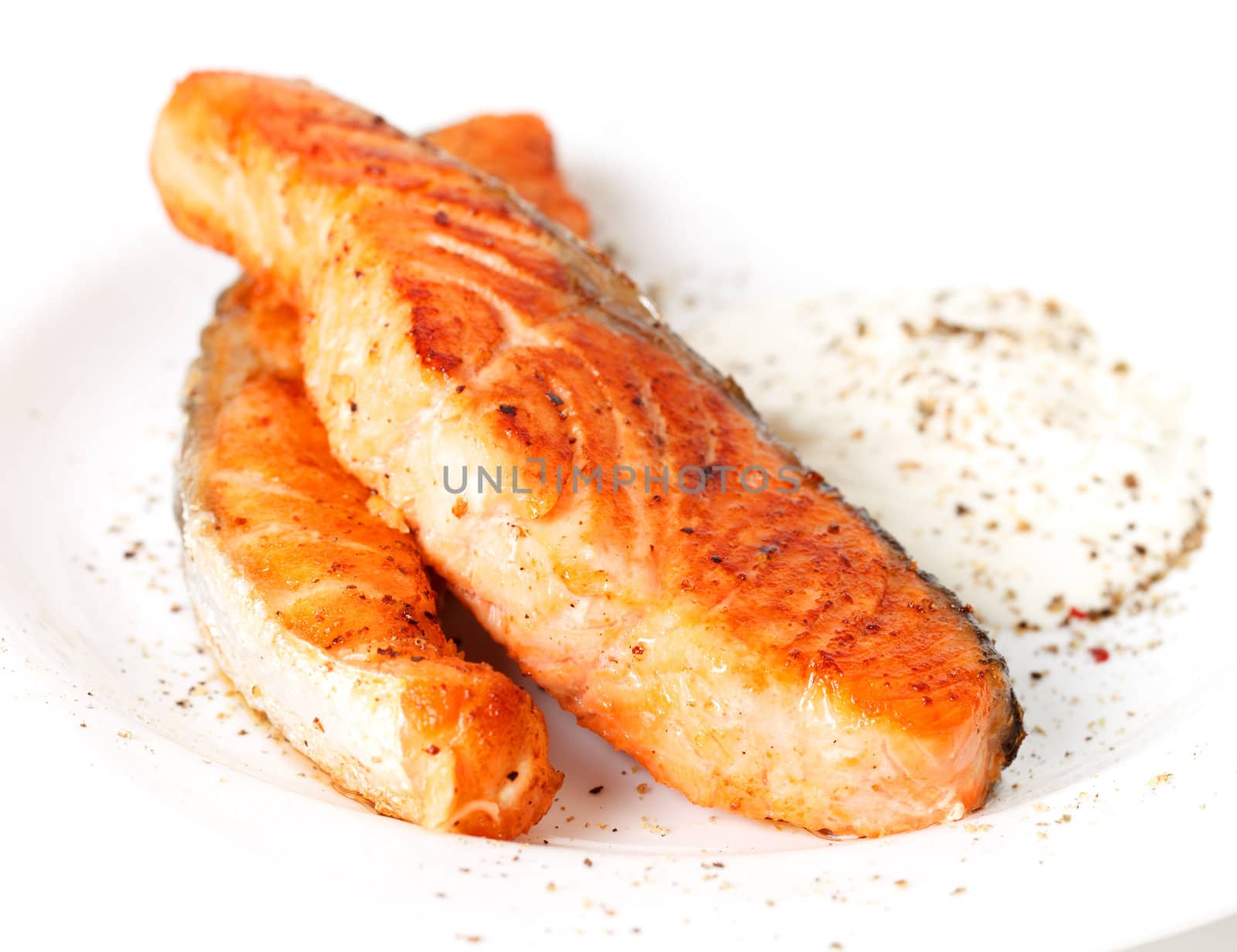 Fried salmon fillets with sauce on white plate