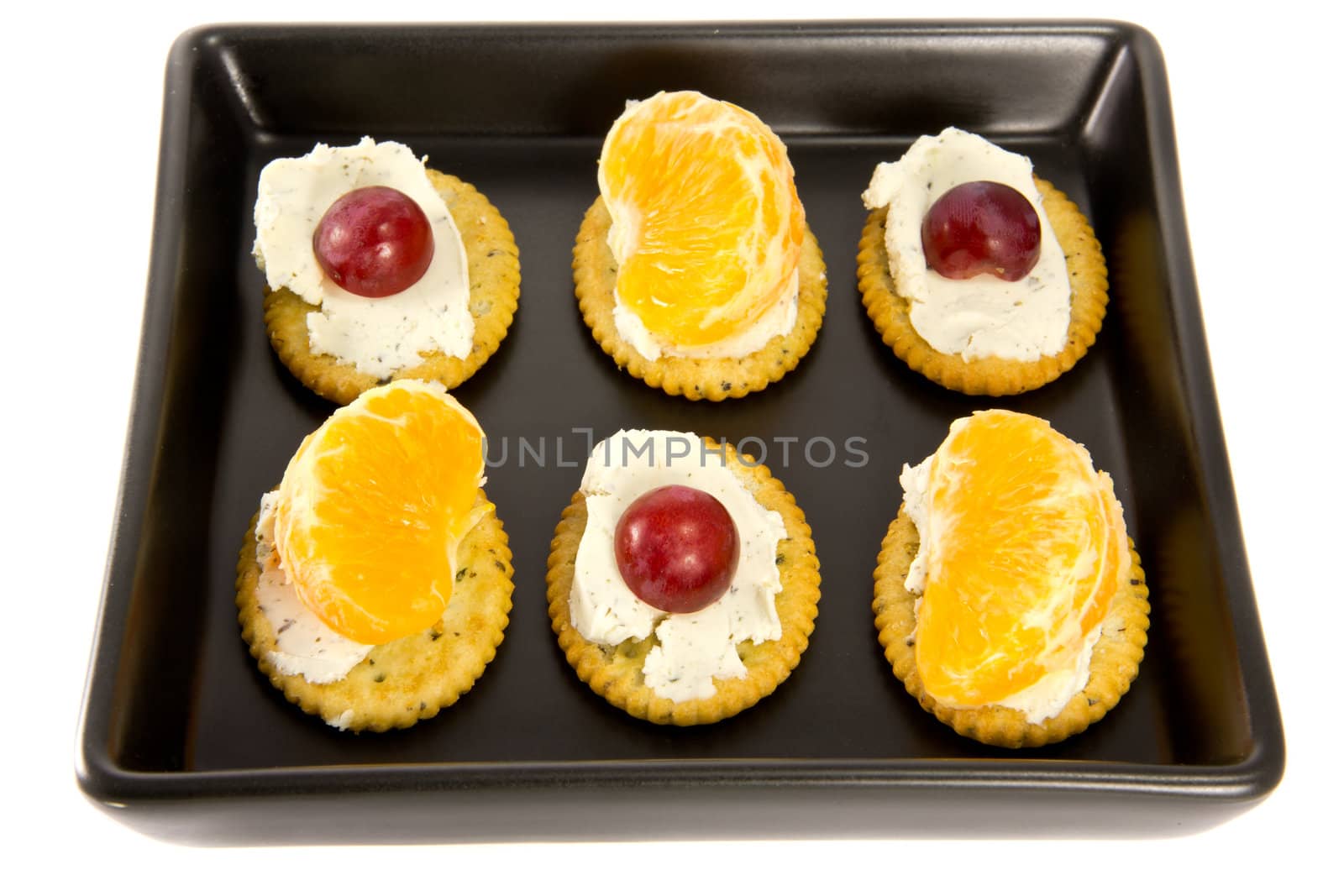 Picture of some crackers with cheese on a black plate