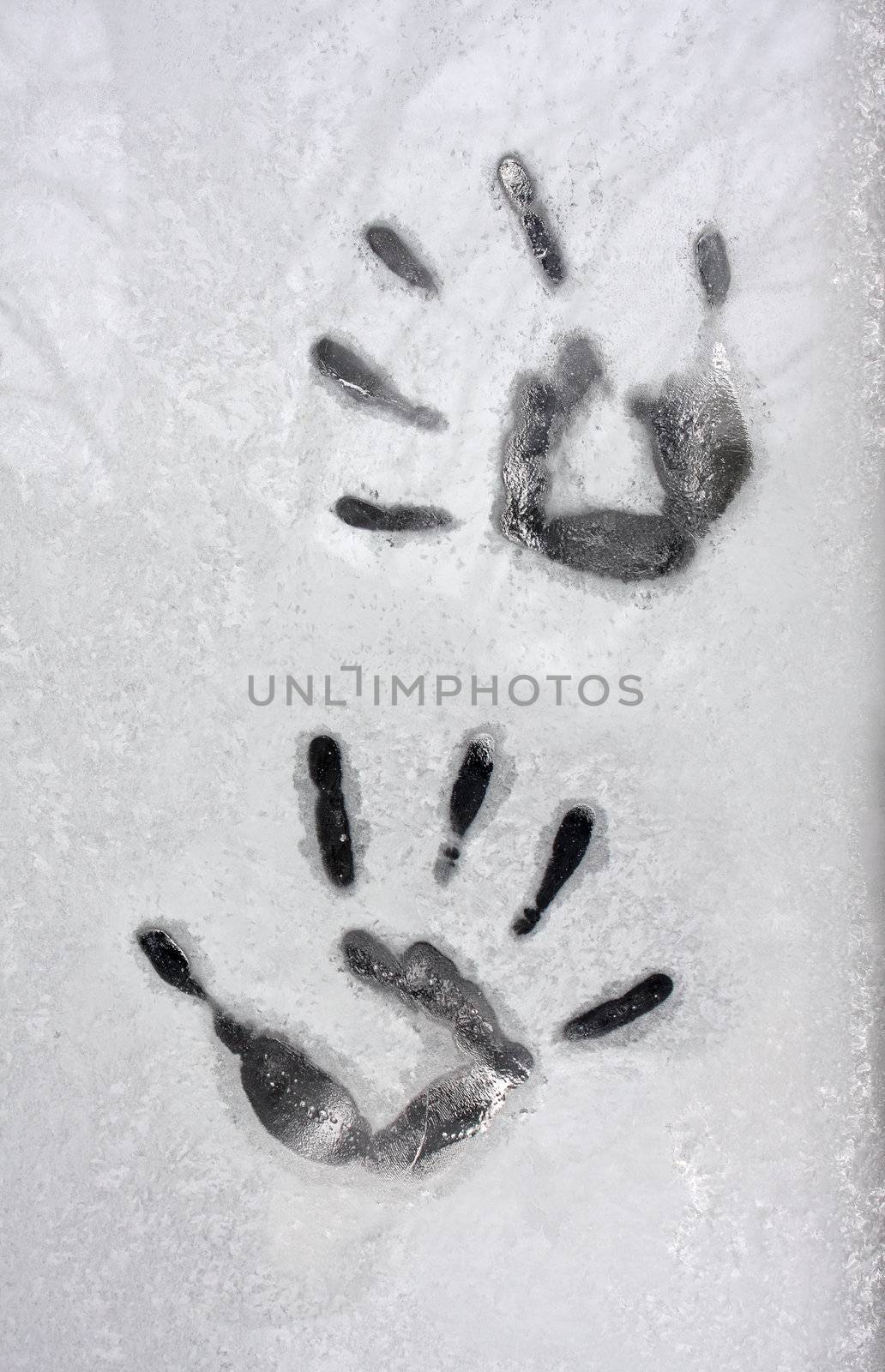 impressions of hands are left on a frost covered window pane