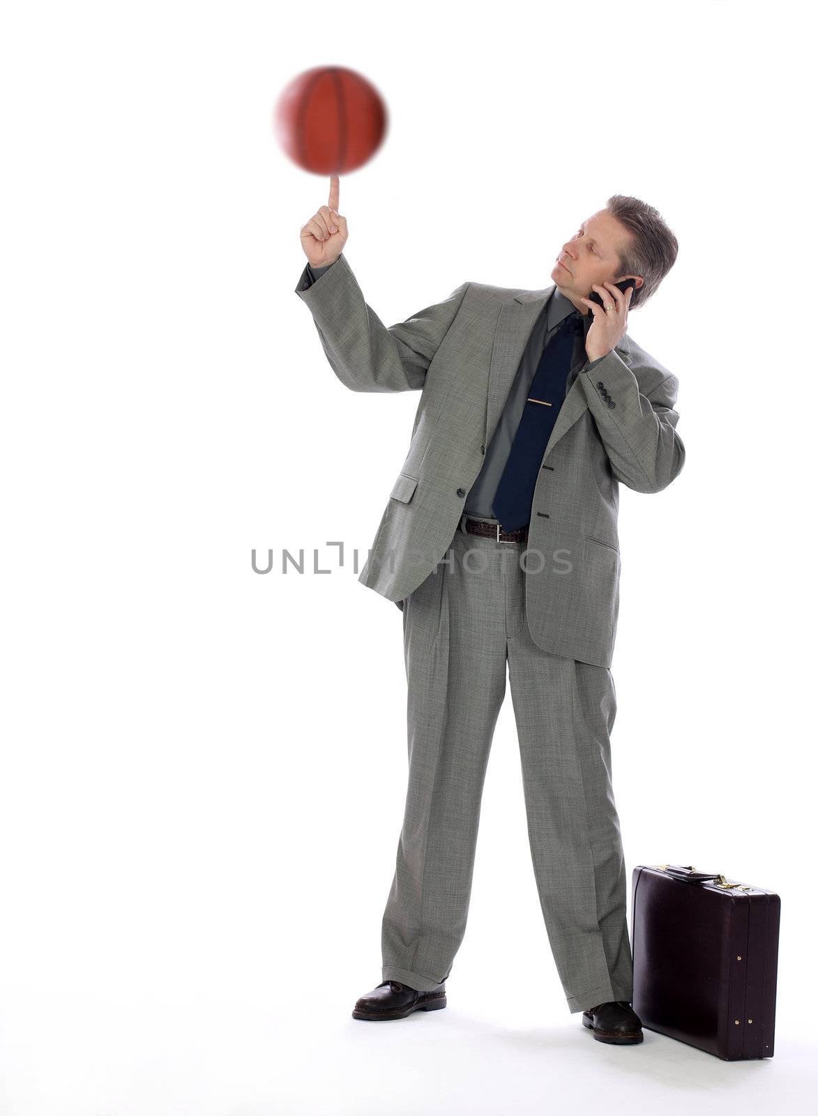 A business man spins a basketball on his finger showing multitasking skills