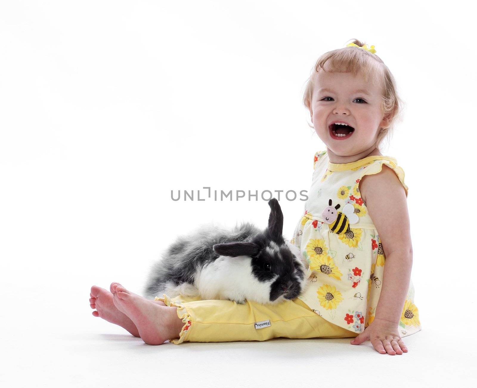 A young girl holds a fluffy bunny rabbit in her lap with loving kindness
