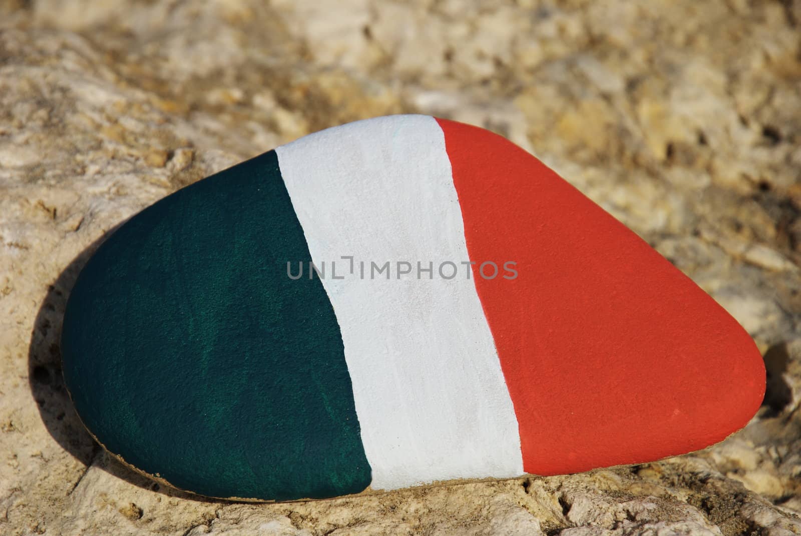 closeup shot over a stone painted with the colours of the italian flag over a rock
