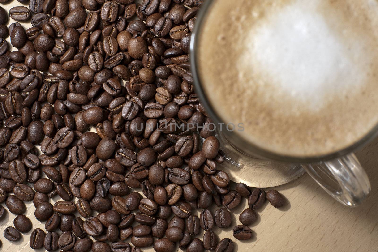 Coffee with froth and coffee beans below on the table