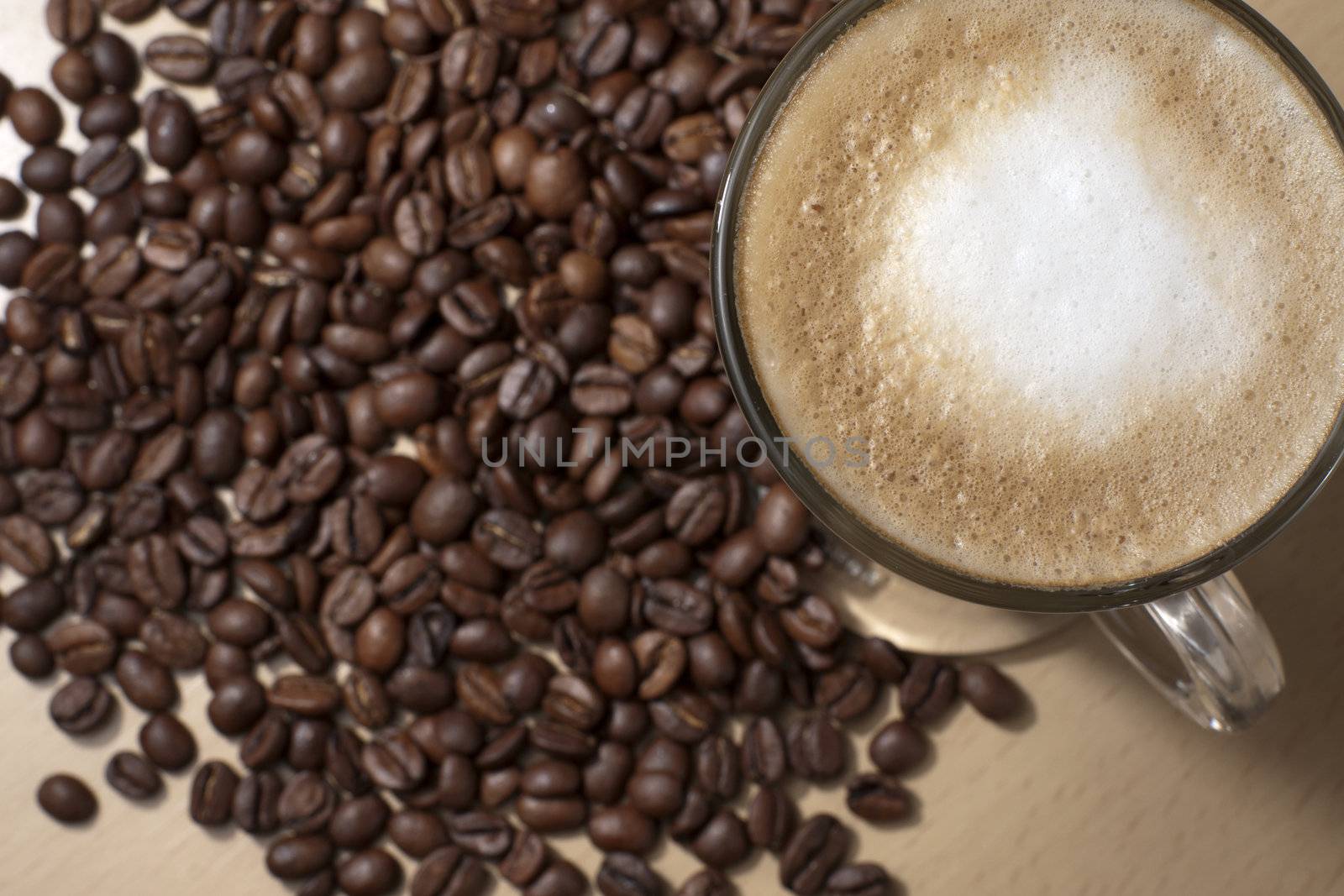 Coffee with froth and coffee beans below on the table
