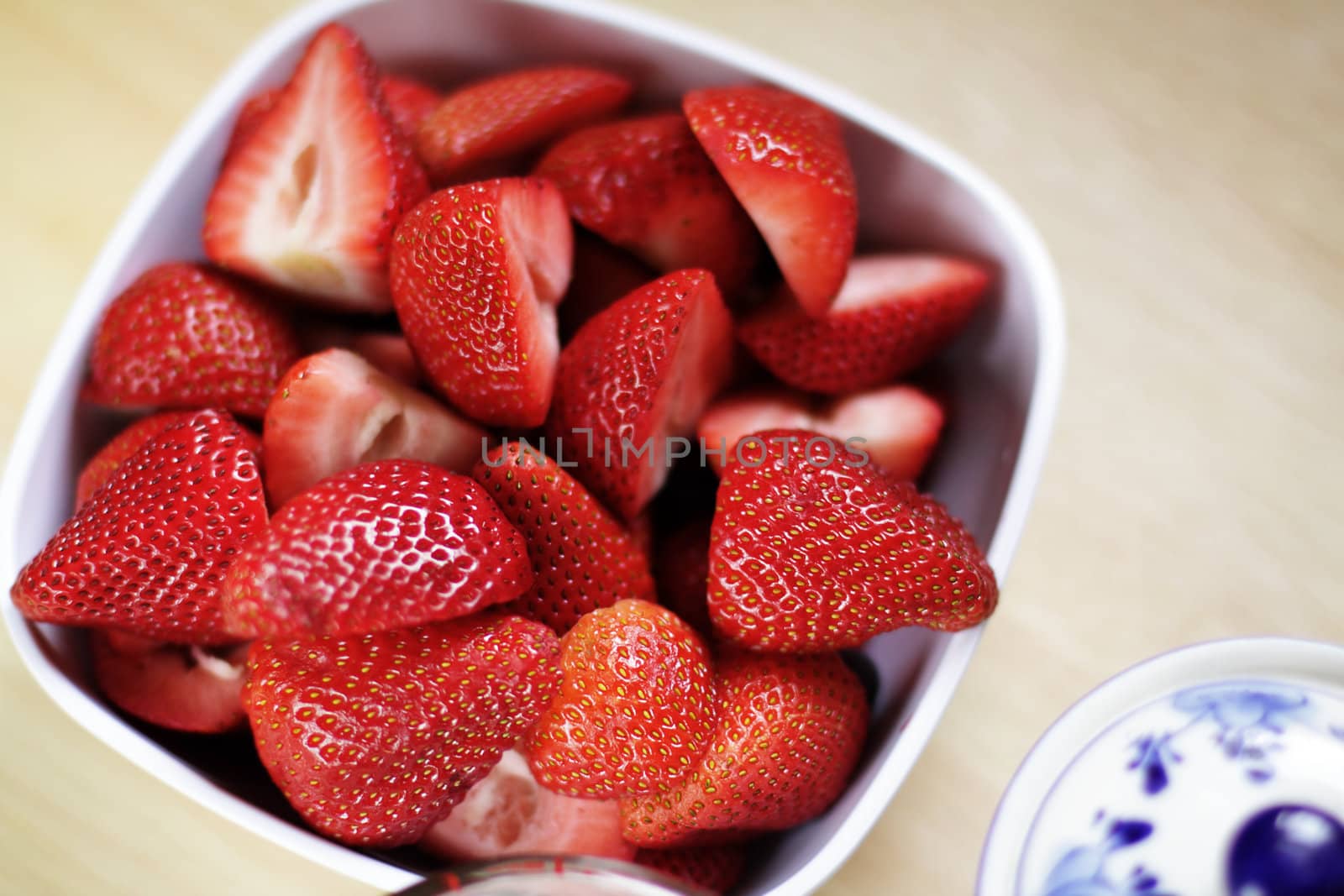 Close-up photo of strawberries in white bowl on kitchen table