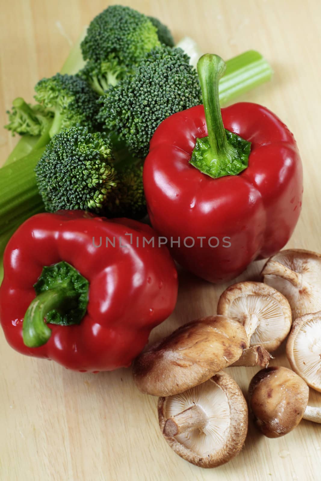 Vegetables on kitchen table: red peppers, broccoli, celery and shiitake mushrooms