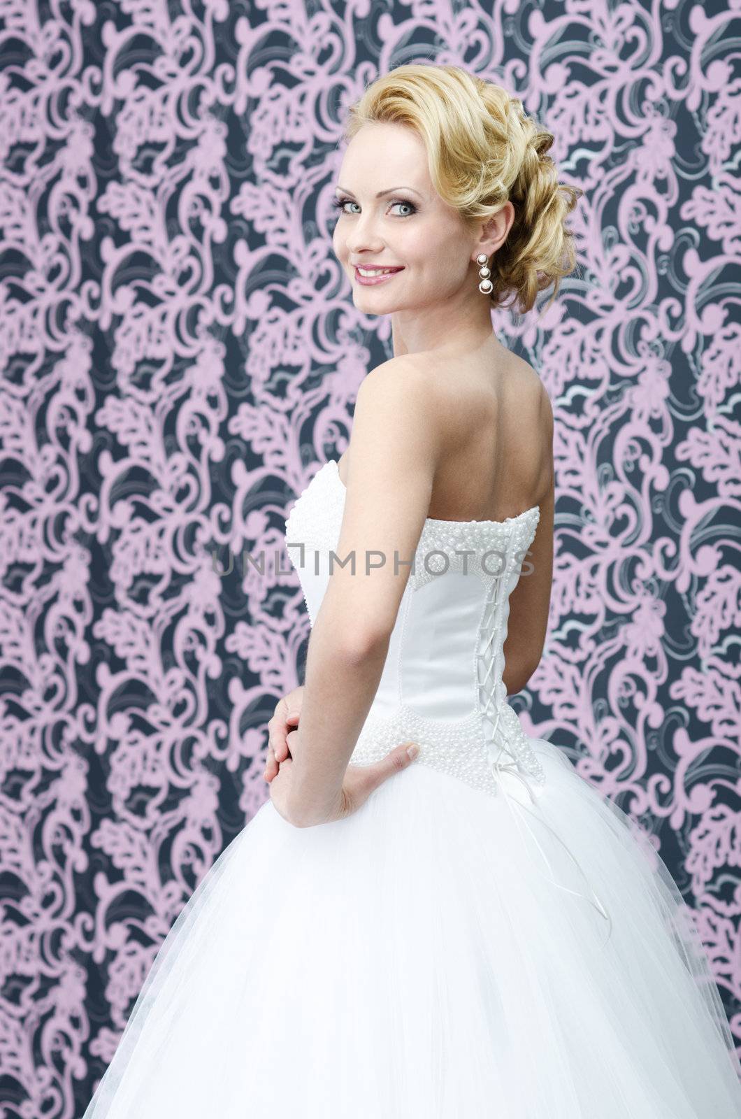 20s yeared bride in white dress is looking back over the shoulder with smile on her face