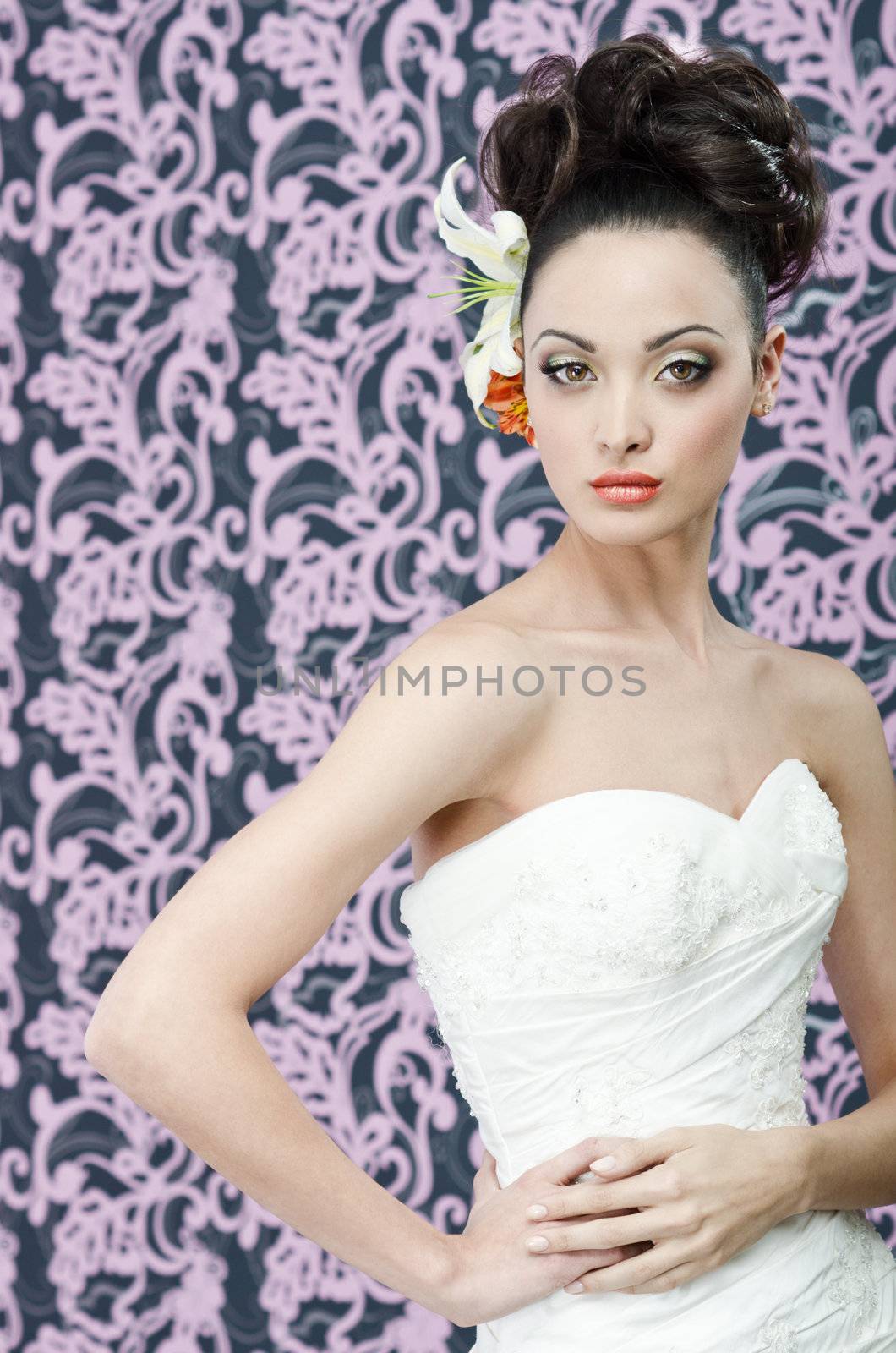 Young adult bride in white wedding dress posing over magenta wall. Her hair decorated with lily flowers