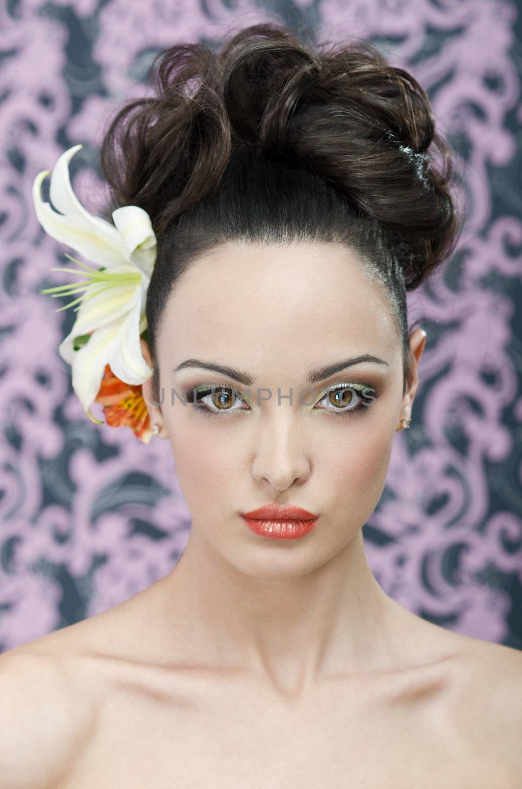 Close up beauty head shot of 20 yeared young adult woman with make-up, hair style and lily flowers in hair. Hi-end retouch except flying hairs around the head