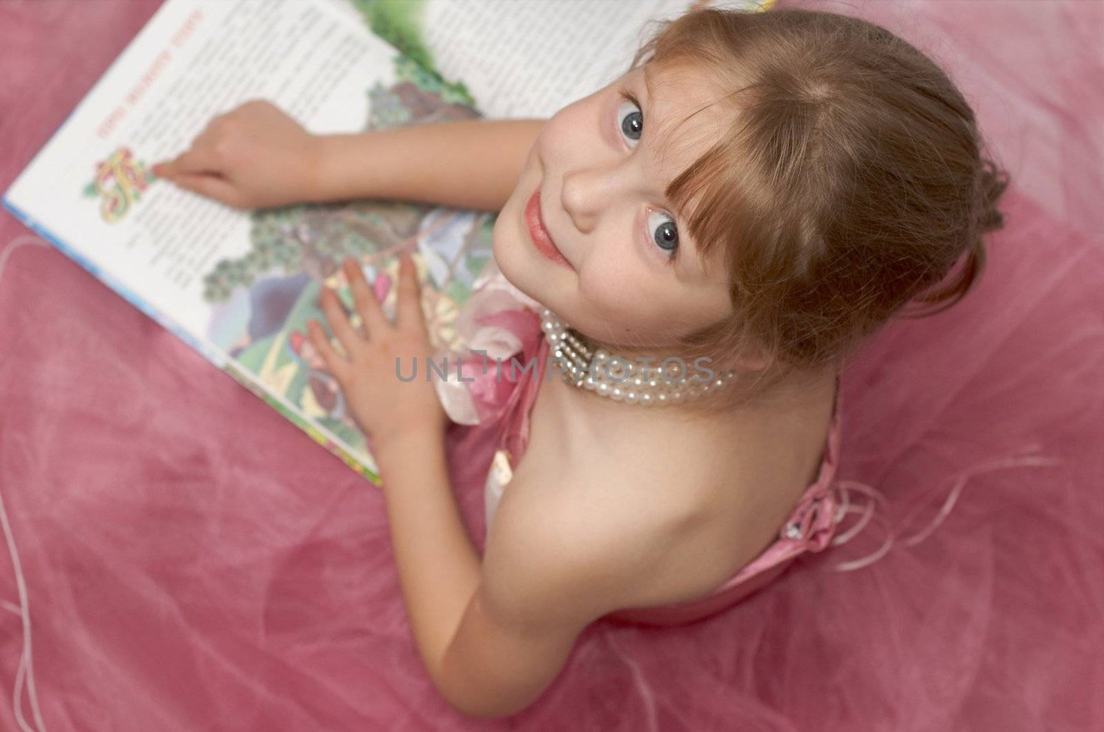 A girl in a pink dress reading a book