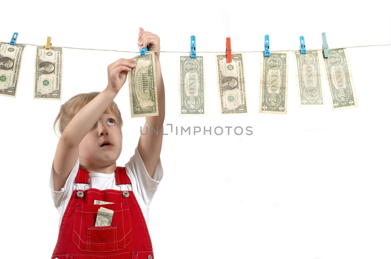 A girl in red overalls hanging up dollars