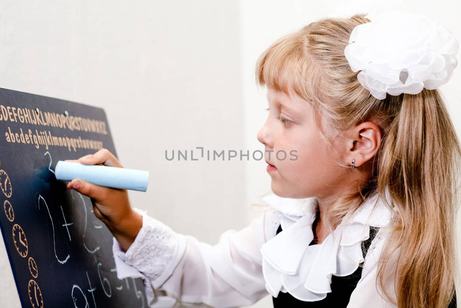 An image of Little girl writing on blackboard.