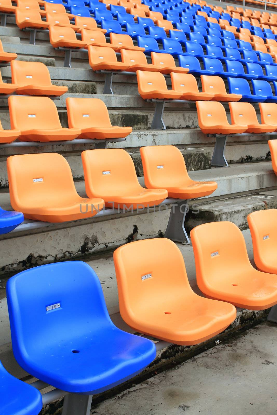 plastic, yellow and blue, new chairs in stadium. by rufous