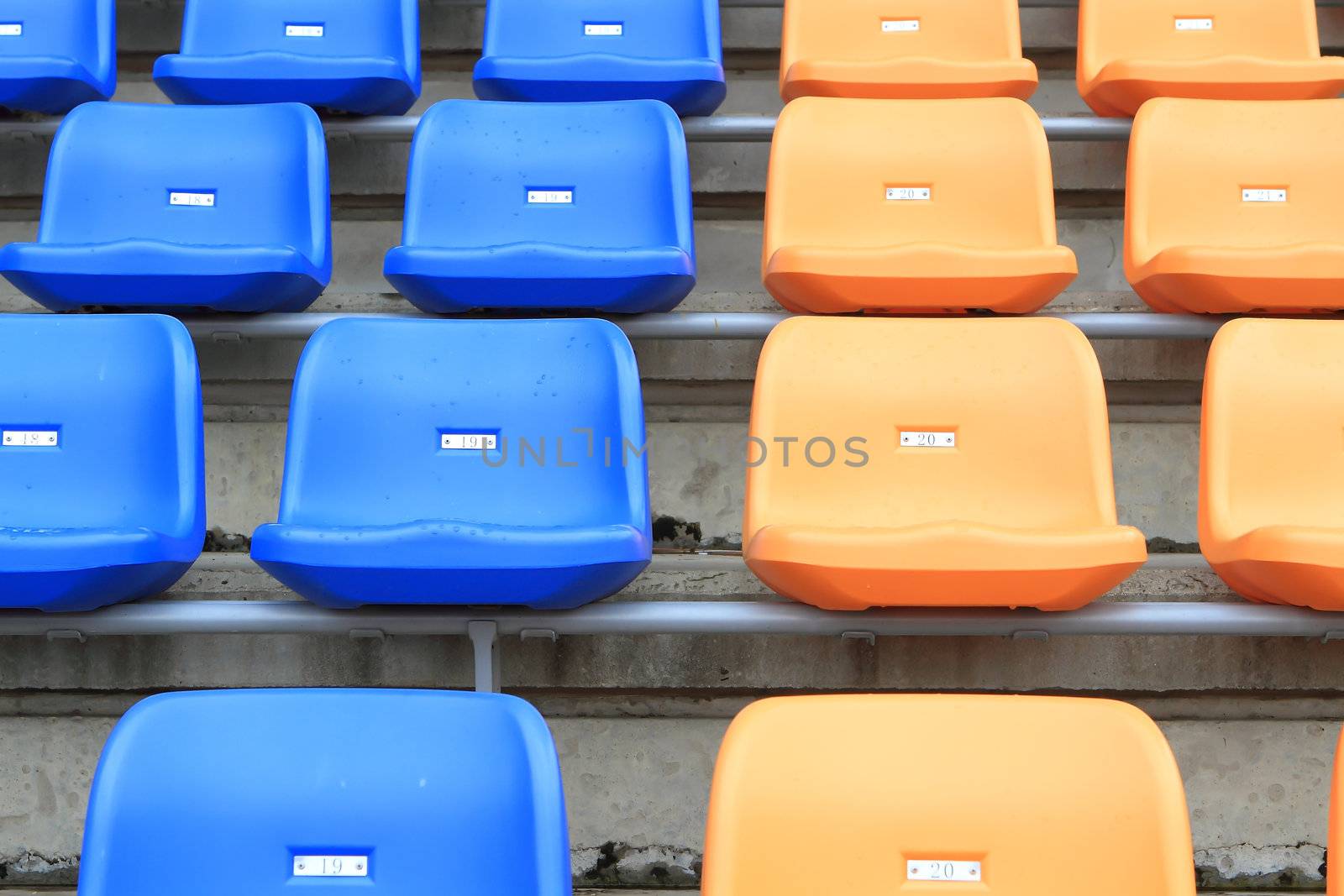 plastic, yellow and blue, new chairs in stadium. by rufous