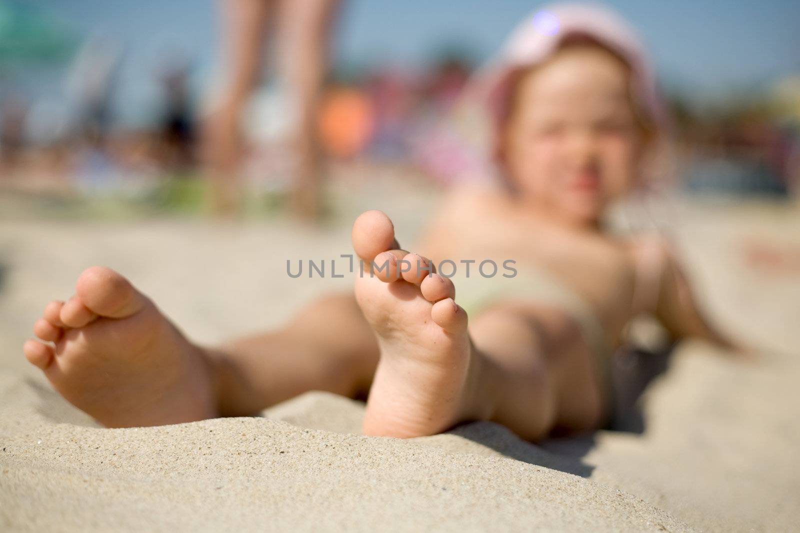 A  little girl on the sand with her feet close-up