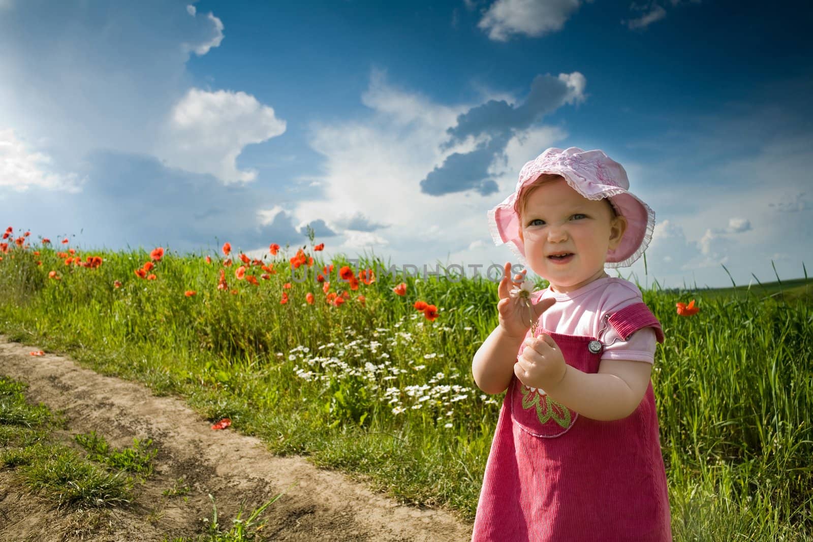 Nice girl with flower on the lane amongst green field