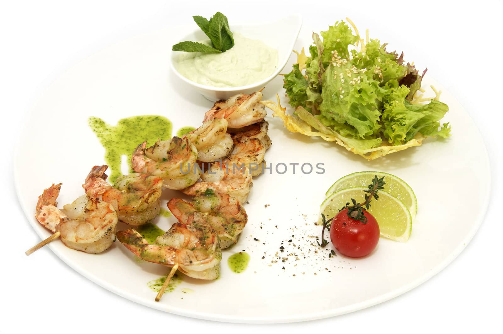 skewers of shrimp on a white plate with greens