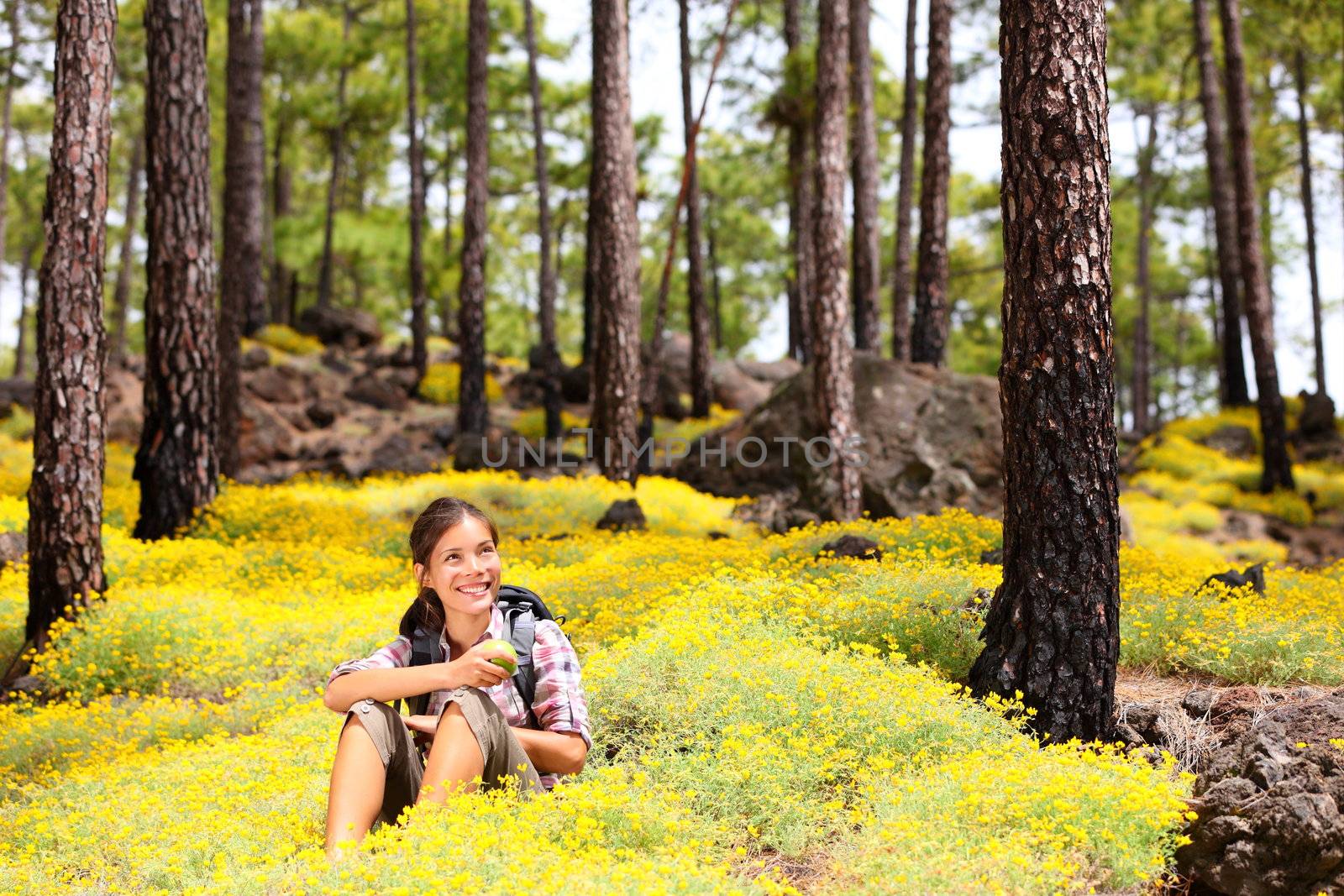 Woman hiker sitting relaxing after hiking eating apple in spring flowers in forest floor. Forest landscape, From Tenerife, Canary Islands, Spain