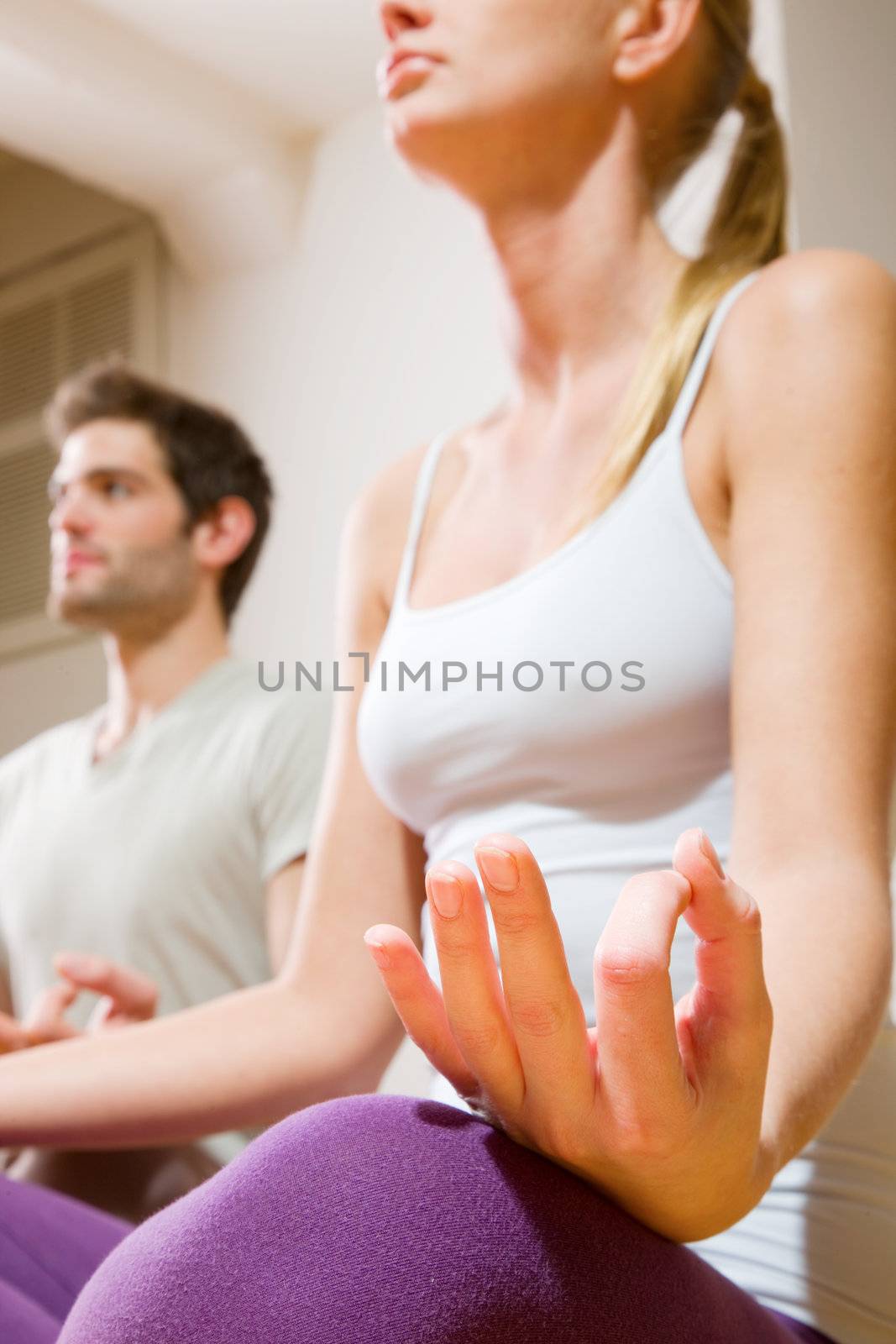 couple sitting on floor doing yoga by ambro