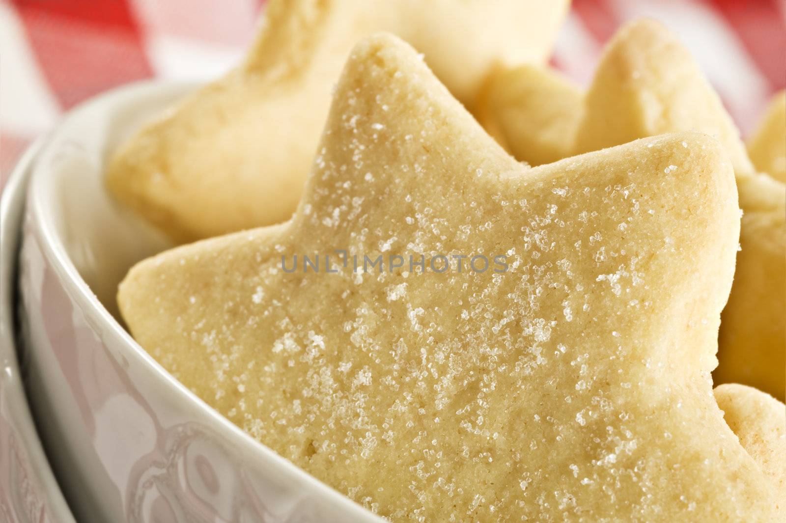 Sugar coated shortbread cookies in star shapes stacked up - on a white background with space for text