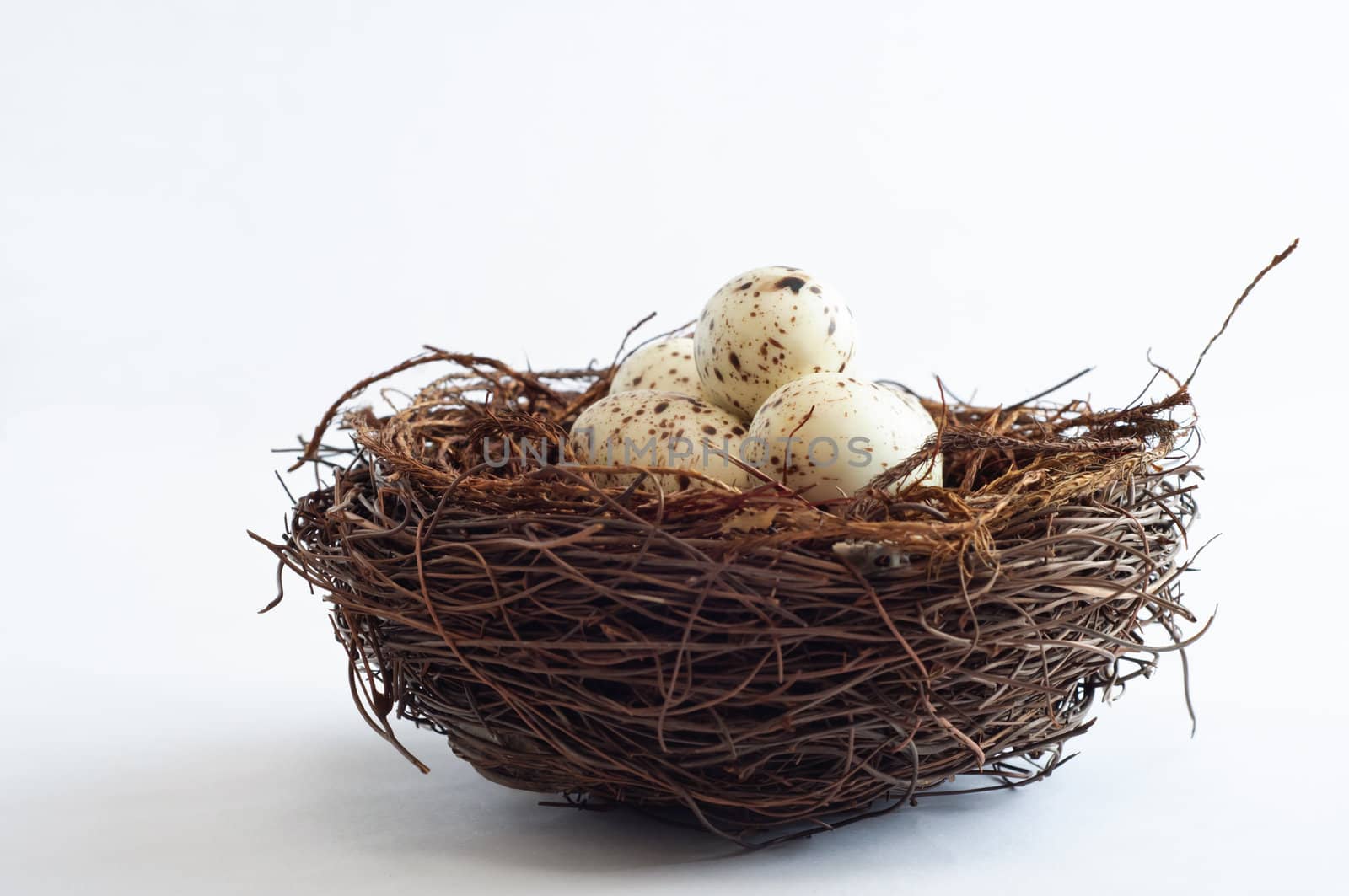 A bird nest made from twigs, containing light speckled fake eggs.