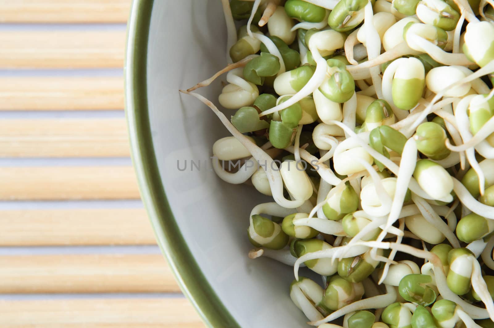 Overhead close up of a bowl of Mung beansprouts on bamboo placemat with copy space.