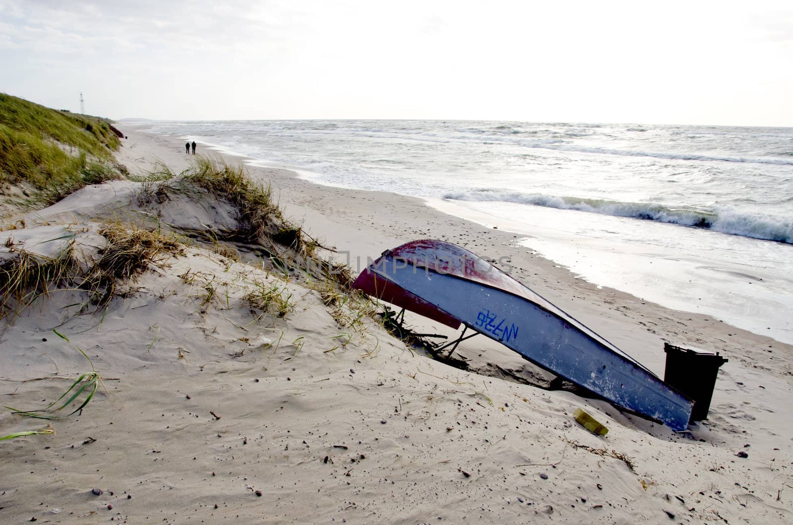 rusty boat lie on sea sand dunes beach people walk by sauletas